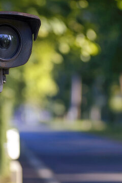 Camera installed on a metal pole near a street, capturing footage of passersby. vertical frame