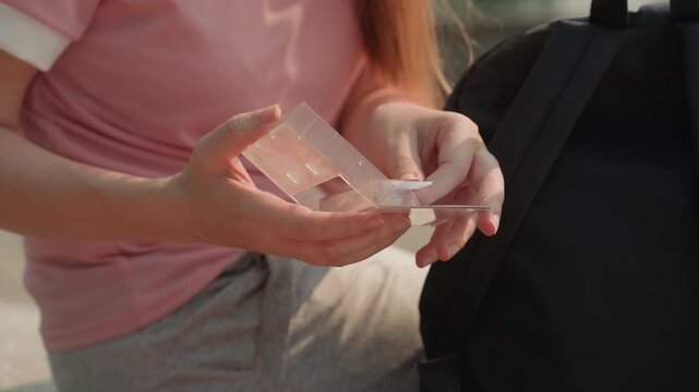 Young woman in pink shirt carefully examines and manipulates clear plastic geometric shapes likely for educational or craft purposes. Woman holds transparent objects against soft natural
