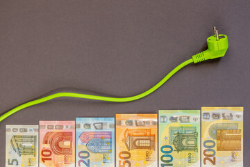 EU green energy economics: rising electricity prices. A green cable and increasing euro banknotes...