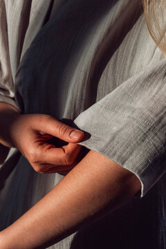 Close up of a woman holding the sleeve of a grey linen garment
