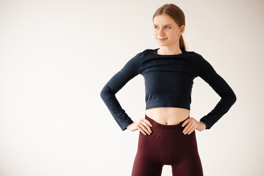 Young woman in athletic wear posing confidently with hands on hips