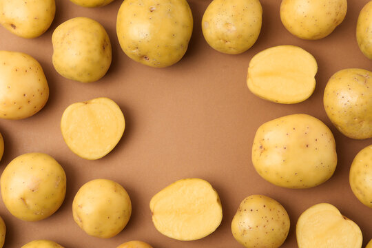 Frame of ripe raw young potatoes on light brown background, flat lay. Space for text