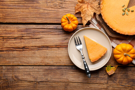 Delicious pumpkin pie, pumpkins and leaves on wooden table, flat lay with space for text. Pastry for Thanksgiving day or other fall holiday