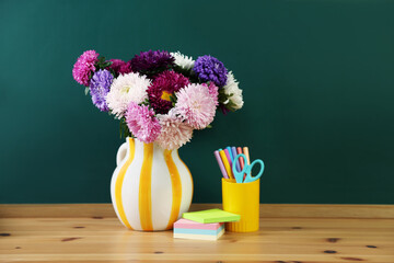Different stationery and beautiful flowers on wooden table near chalkboard © New Africa