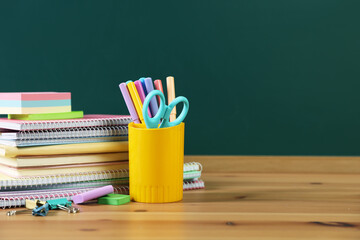 Different stationery on wooden table near chalkboard. Space for text © New Africa