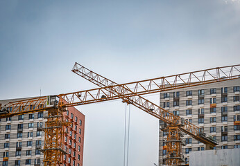 Two yellow construction cranes working at a high-rise building site against a clear sky © LemPro Filming Life
