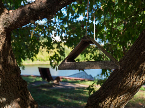 Rustic wooden bird feeder hanging on a tree in a park by the lake