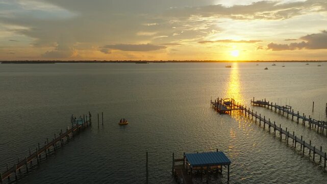 Aerial Sunset Over Stuart, Florida Waterfront Docks and Palm Trees With Golden Reflection