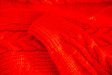 Fototapeta premium red knitted sweater texture with soft wool threads and cozy stitches, warm winter clothing background, handmade feel, detailed fabric pattern, comfortable seasonal apparel