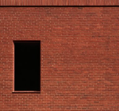 Red brick wall with a single dark, empty window and textured detail