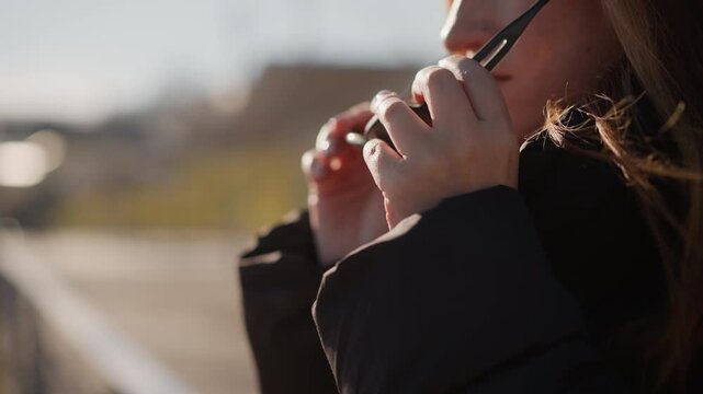 Woman examines and uses pair of metal pliers outdoors in daylight wearing sunglasses and winter clothing. background shows out of focus landscape with natural light and soft shadows