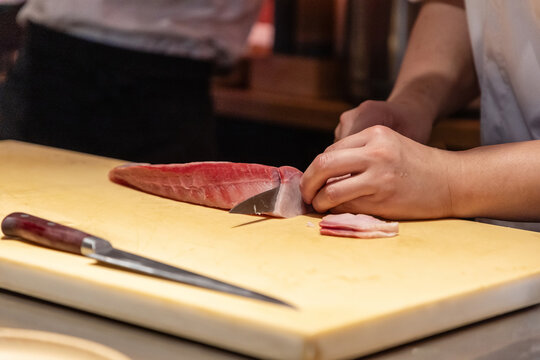 Skilled chef preparing fresh fish on wooden cutting board with knife
