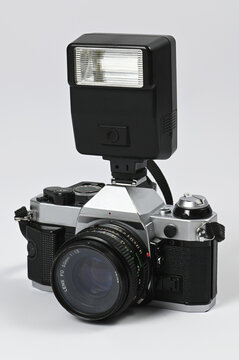 An old analog film camera with a built-in flash on a white background
