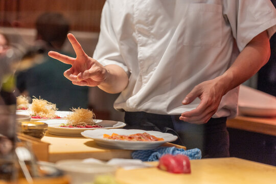 Chef preparing sushi dishes with artistic presentation in restaurant kitchen