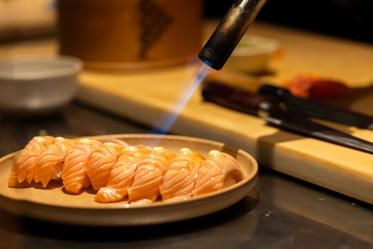 Sushi preparation with blowtorch highlighting culinary artistry and technique