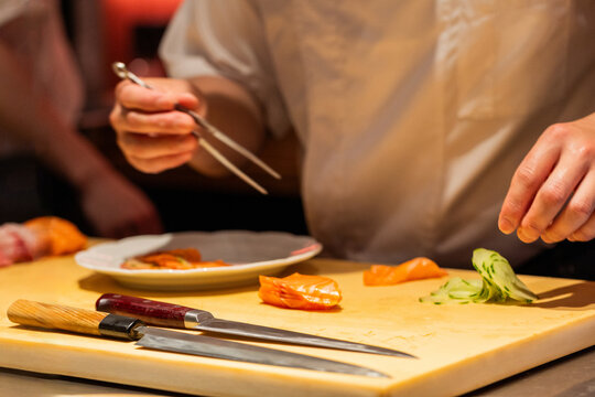 Chef preparing sushi with precision using chopsticks and sharp knives