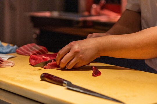 Skilled chef slicing fresh fish on wooden cutting board in kitchen