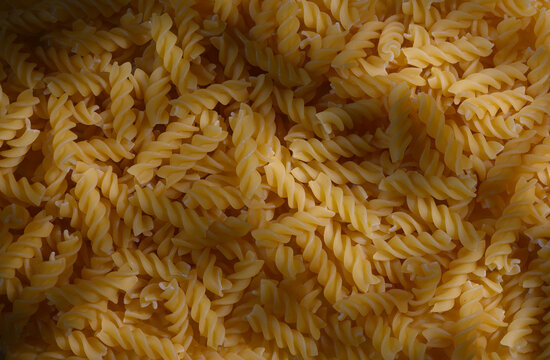 Commercial food photography of a top-down background of dry fusilli pasta with moody shadows