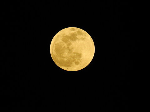 Golden full moon isolated on clear black night sky background.