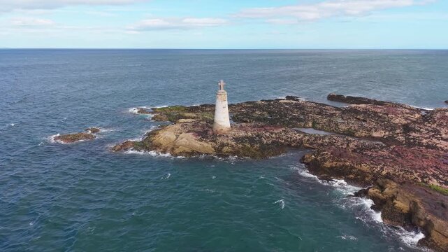 Close up aerial orbit view of St Baldreds Cross on coastal rocks at North Berwick Scotland