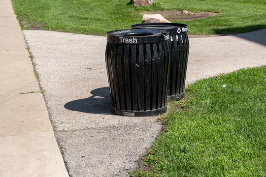 Black recycling bins in a public park for collecting different types of waste, representing recycling, waste separation, and environmental responsibility