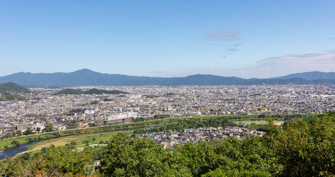 Panoramic view of Kyoto cityscape surrounded by green hills and distant mountains under wide blue sky with soft clouds, Kyoto, Japan