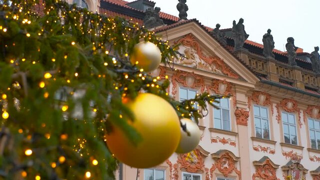 Christmas tree decorating prague's old town square. Ornate christmas tree with glowing lights and golden baubles standing in front of historic rococo architecture in the old town square of prague