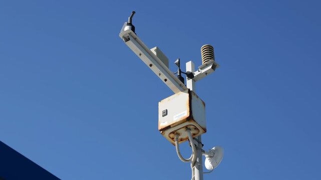 Weather station anemometer spinning against blue sky