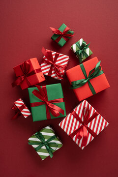 Merry Christmas gift and present flatlay with red and green ribbons for happy New Year celebration on vertical burgundy desk