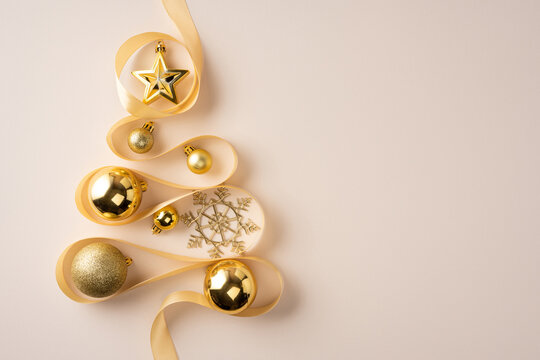 Golden Christmas ornaments and ribbon arranged as a minimalist tree for Merry Christmas and Happy New Year