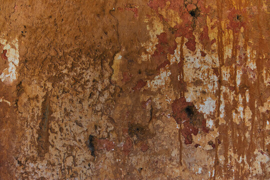 Rough terracotta mud wall texture with dripping rust-colored stains