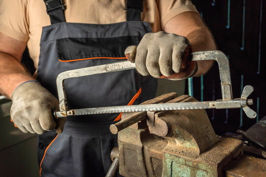 A skilled artisan carefully uses a hacksaw to cut metal, showcasing their focus and craftsmanship. The warm light of dusk enhances the workshop's atmosphere