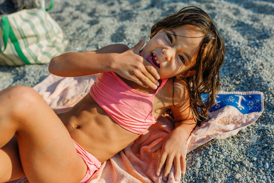 Happy Child Lying on Beach Towel Pointing at Missing Tooth