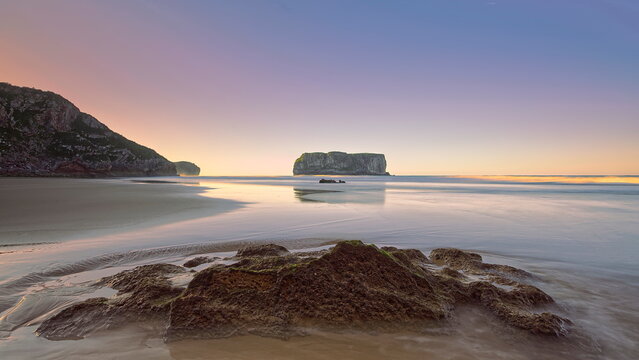 Spectacular sunset on Playa Andr&iacute;n Beach at low tide with Castro Ballota islet in the background, across the wave-wet sand. Llanes-Asturias-Spain-085
