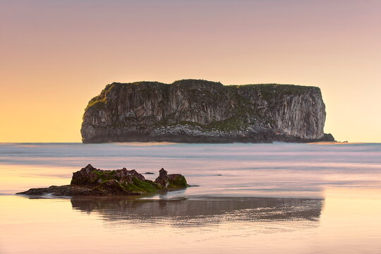 Spectacular sunset on Playa Andr&iacute;n Beach at low tide with Castro Ballota islet in the background, across the wave-wet sand. Llanes-Asturias-Spain-086