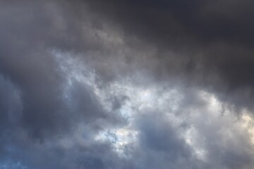 Fototapeta premium Dark storm clouds with light breaking through dramatic overcast sky background