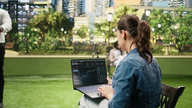Woman using laptop with trading platform and candlestick chart