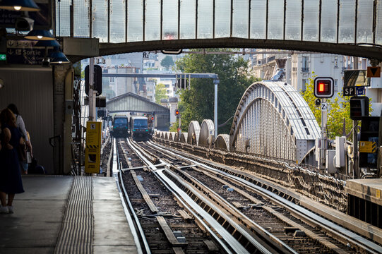 Elevated metro tracks and arched bridge leading to a station with trains in Paris France