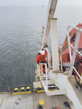 seafarers working for greasing life boat davit