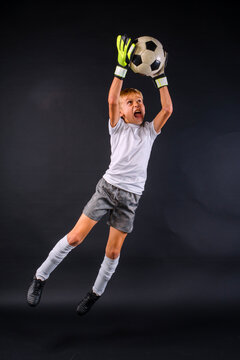 Action shot of a male youth soccer player with goalie gloves leaping to catch soccer ball