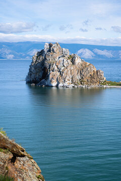 Shamanka rock formation on Olkhon island in Lake Baikal, Russia. Vertical landscape photo of the famous natural landmark in Siberia with blue water and mountains