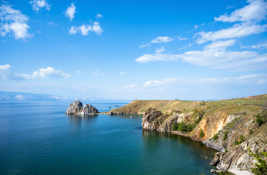Landscape of Lake Baikal with Shamanka stone on Olkhon island. Wide view of deep blue water and rocky coastline on a sunny summer day. Copy space in the sky background, nature of Siberia