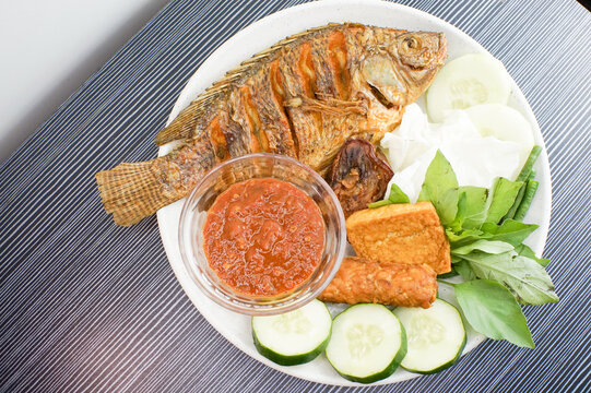 Delicious Indonesian Fried Tilapia Fish with Sambal and Fresh Vegetables.
