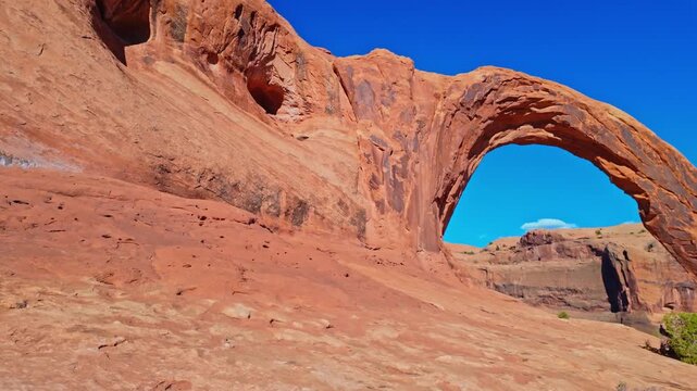 Golden evening light bathes the towering sandstone curve of Corona Arch rising above Bootlegger Canyon near Moab Utah