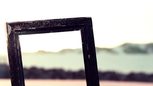 A rustic frame stands against a stunning backdrop of a gentle sunset illuminating the sky above a calm beach. The scene radiates peaceful vibes, inviting reflection.