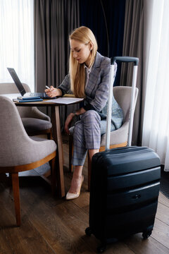 Businesswoman combining laptop work with handwritten notes for work. The side composition shows organized work while traveling.