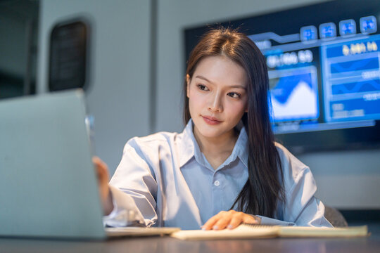 Smiling Asian business woman using laptop in modern digital workplace, Female corporate worker analyzing data technology in office, Financial management, software dashboards and tech startup concepts