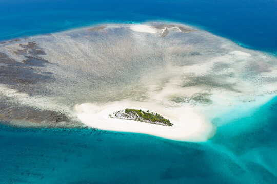 Colorful, turquoise water and coral reef surrounds the tiny, idyllic island of Kaniungan-kecil off the coast of East Kalimantan, Indonesia. This scenic region harbors spectacular marine biodiversity.
