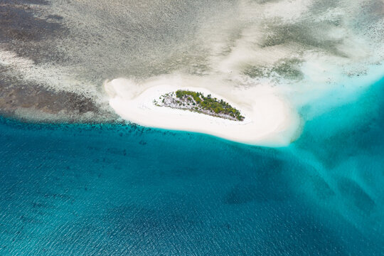 Colorful, turquoise water and coral reef surrounds the tiny, idyllic island of Kaniungan-kecil off the coast of East Kalimantan, Indonesia. This scenic region harbors spectacular marine biodiversity.