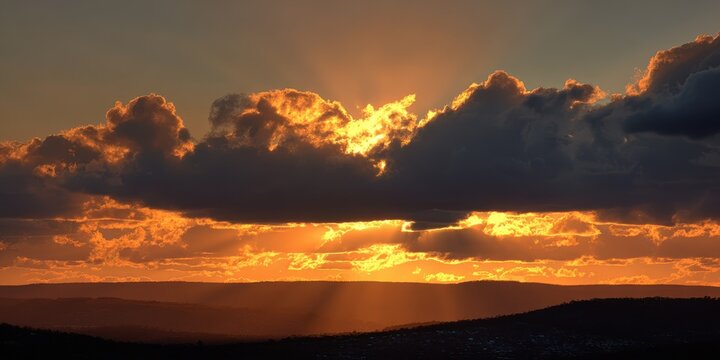 Breathtaking sunset illuminating rolling hills featuring dramatic cloud formations and radiant beams of light